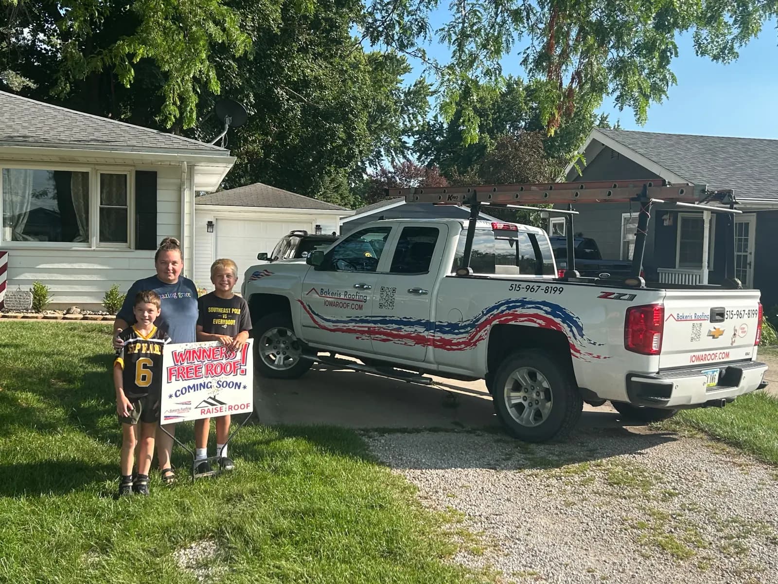 The Carr family holding their Winner Free Roof sign beside a Bakeris Roofing truck on announcement day